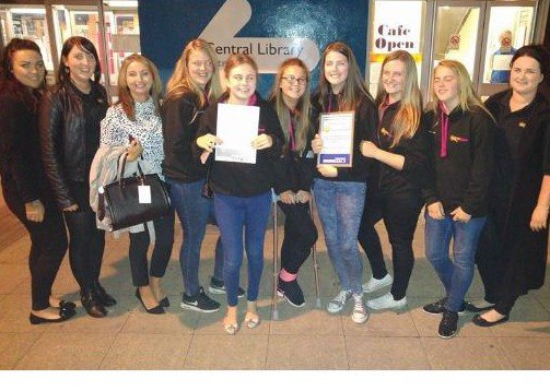 A group celebrating with certificates at a local library