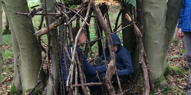 Young people building a den in the woods