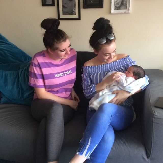 Two young mothers, one holding a baby