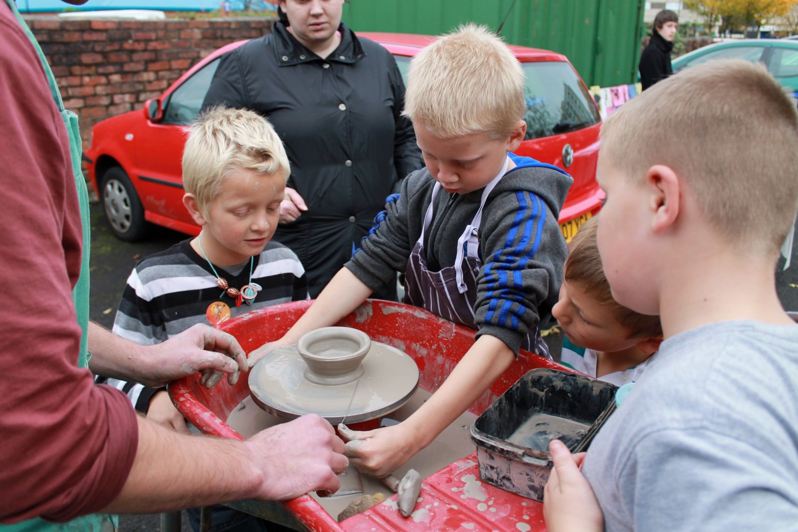 Children at a Kids Kabin street pottery session, shaping clay on a potter's wheel