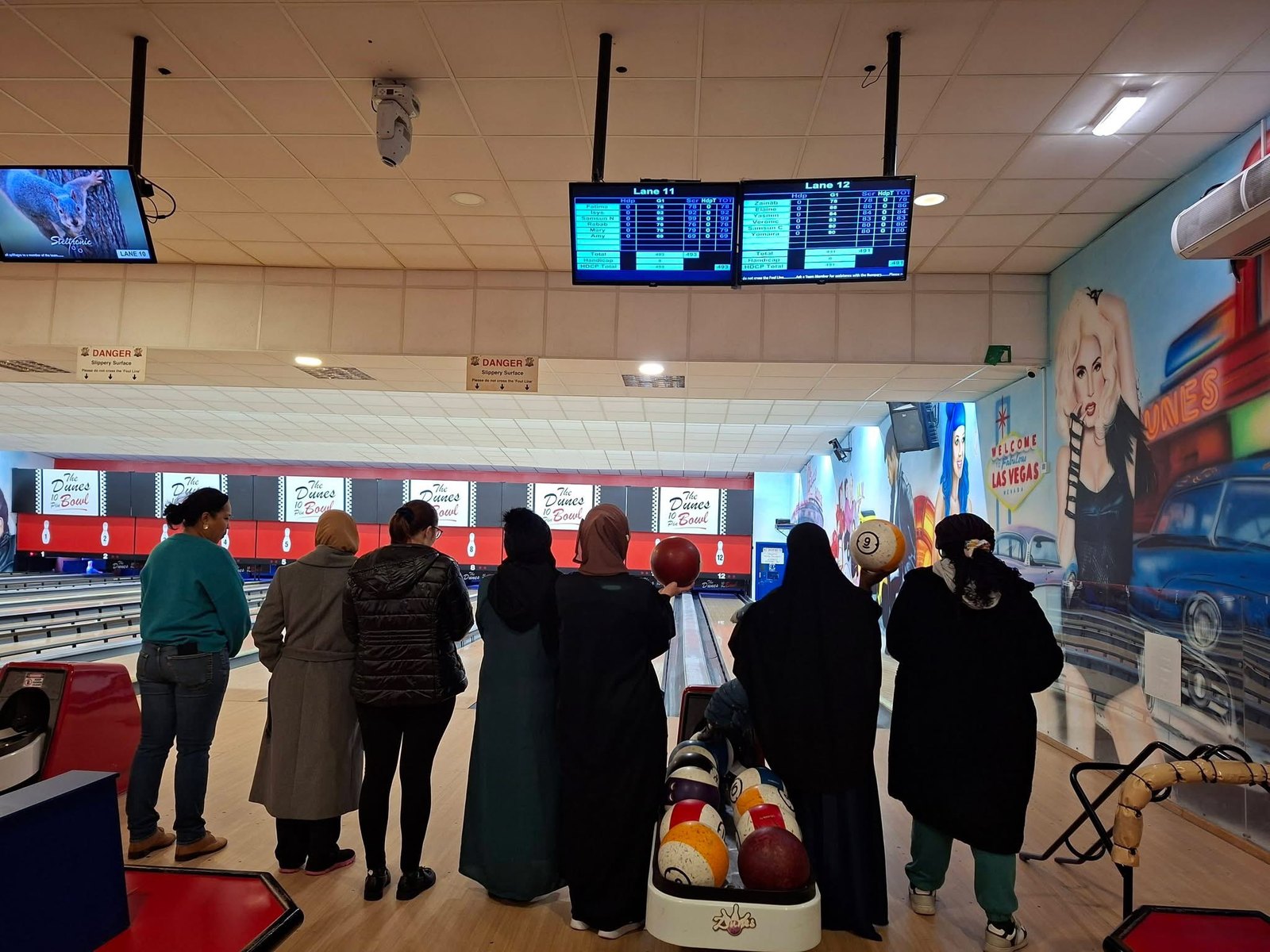 A group of women standing together at the end of a bowling lane