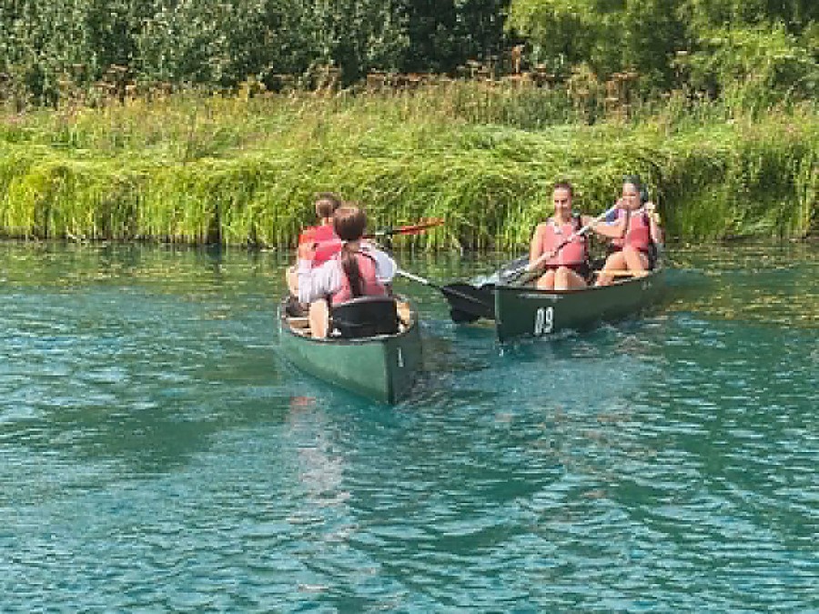 Two canoes of young people paddling together on open water