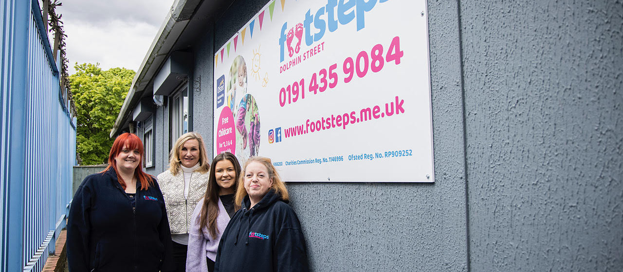 Four members of nursery staff standing outside a building beneath a Footsteps nursery sign