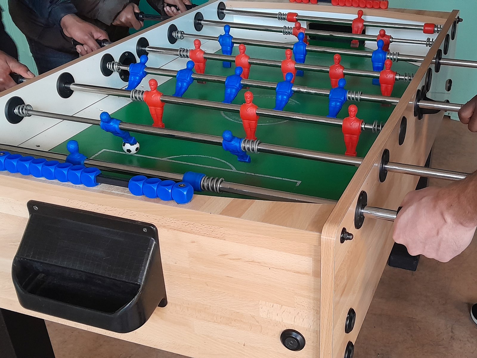 Hands gripping the handles of a table football game, mid match